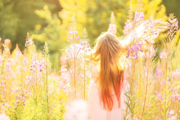 Chica feliz en un campo con flores — Foto de Stock