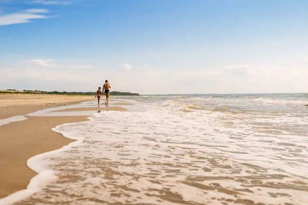 Baba ve kızı yaz sezonunun sonunda denizin yanından geçiyor.