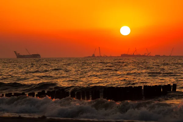 Baltık Denizi'nde gün batımı. Turuncu gökyüzü ve sörf.