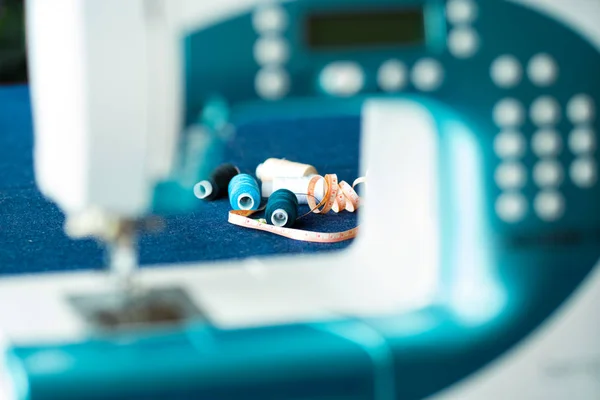 Dikiş için denim ve iplik ile dikiş makinesi, yakın çekim. Mavi bezli dikiş makinesinin bir parçası.