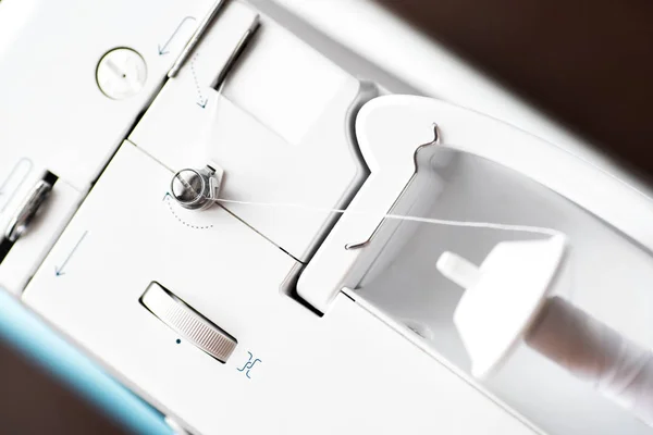 Dikiş için denim ve iplik ile dikiş makinesi, yakın çekim. Mavi bezli dikiş makinesinin bir parçası.