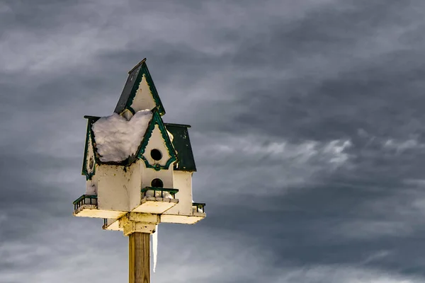 Snowy-covered birdhouse close up with cold winter sky on background — Stock Photo, Image