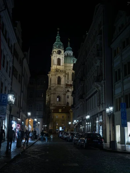 Ulice Pragi Republiki Czeskiej w nocy z kościołem św. Mikołaja w tle — Zdjęcie stockowe