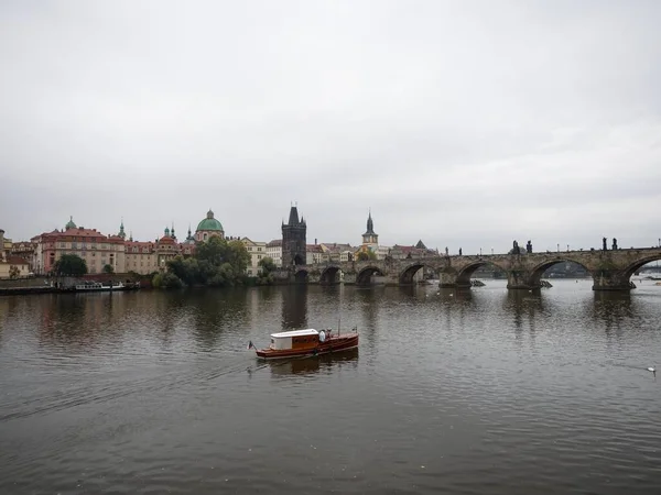 Pequeno barco no rio Vltava em Praga República Checa com a Ponte Charles no fundo em um dia nublado — Fotografia de Stock