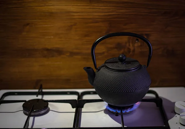 stock image Iron teapot on gas stove in the kitchen with wooden background