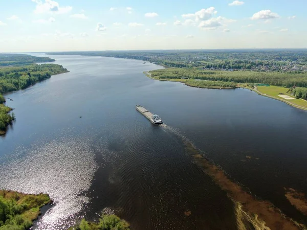 stock image Aerial view the cargo ship floats down the river surrounded by forest. Beautiful panoramic landscape from the height