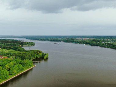 Açık ambarları olan büyük bir kargo gemisinin üzerinden uçmak ormanla çevrili sakin bir nehirde yelken açmak. Malları nehirden taşıyoruz. Güzel panoramik manzara. Üst görünüm aşağı