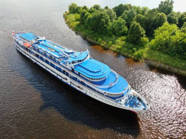 Hava manzaralı nehir yolcu gemisi, yazın güneşli bir günde güzel yeşil ormanlarla çevrili nehir boyunca yelken açar. Seyahat Gemisi Gezisi