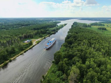 Hava manzaralı nehir yolcu gemisi, yazın güneşli bir günde güzel yeşil ormanlarla çevrili nehir boyunca yelken açar. Seyahat Gemisi Gezisi