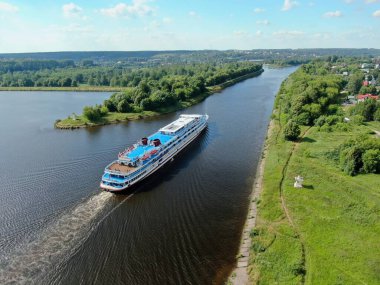 Hava manzaralı nehir yolcu gemisi, yazın güneşli bir günde güzel yeşil ormanlarla çevrili nehir boyunca yelken açar. Seyahat Gemisi Gezisi