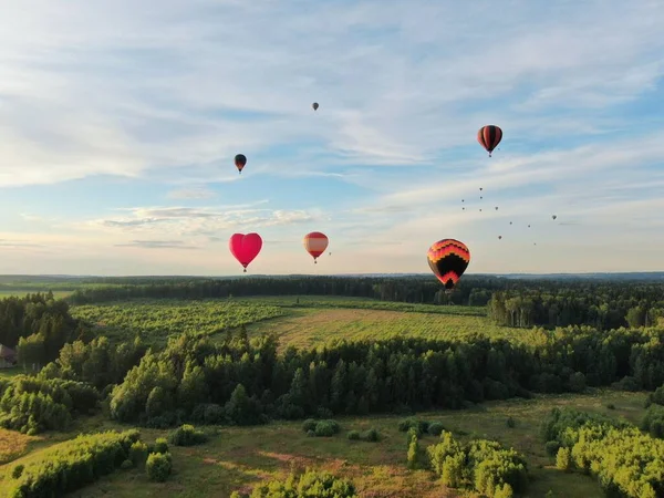夏の日没に青い空を背景に 緑の畑や森の上を気球に乗って飛んでいます ドローン撮影 — ストック写真