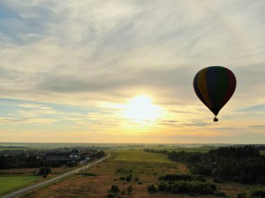 Yazın günbatımında mavi gökyüzünün arka planında yeşil bir tarla ve ormanın üzerinde balonlarla uçmak. İHA atışı