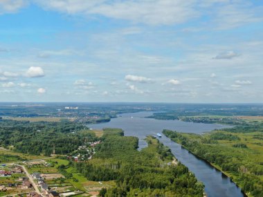 Yolcu gemisinin nehir boyunca yaptığı hava manzaralı yolculuk. Yüksek bir gemiden güzel panoramik manzara su ve bulutların arka planına karşı geniş bir nehir boyunca yelken açar.