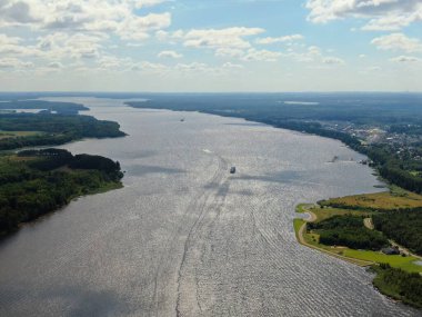 Yolcu gemisinin nehir boyunca yaptığı hava manzaralı yolculuk. Yüksek bir gemiden güzel panoramik manzara su ve bulutların arka planına karşı geniş bir nehir boyunca yelken açar.