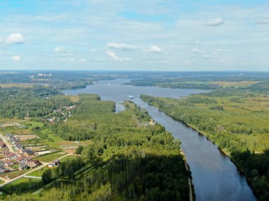 Yolcu gemisinin nehir boyunca yaptığı hava manzaralı yolculuk. Yüksek bir gemiden güzel panoramik manzara su ve bulutların arka planına karşı geniş bir nehir boyunca yelken açar.