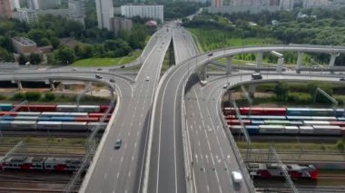 Büyük bir şehirde büyük bir trafik kavşağının havadan görüntüsü. Demiryolunun üstündeki üst geçitte arabalar hareket ediyor.