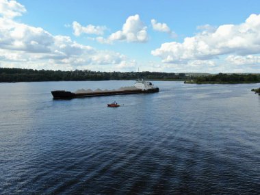 Hava manzaralı kargo gemisi nehir boyunca ilerliyor. Malların nehir mavnalarıyla taşınması. Nehrin güzel manzarası.