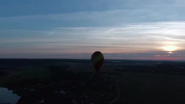 Hava manzaralı romantik balon uçuşu günbatımında büyük kırmızı bir kalp şeklinde. İnsansız hava aracının balonlarının izini sürdüğü güzel panoramik manzara uçuşları