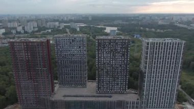 Yeni ofis kuleleri ve alışveriş merkezinin hava manzaralı inşaatı. Yeşil ormanın arka planına karşı şehir manzarası