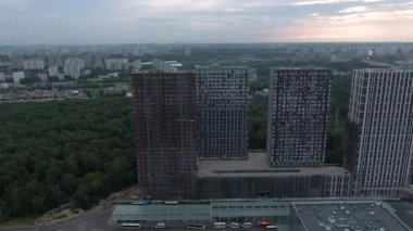 Yeni ofis kuleleri ve alışveriş merkezinin hava manzaralı inşaatı. Yeşil ormanın arka planına karşı şehir manzarası