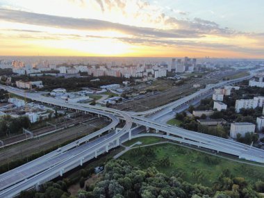 Gün doğumunda Moskova 'nın panoramik manzarası. Şehirdeki bir otoyolda, altın güneş ışınlarının altında çok katlı bir kavşak. İHA atışı