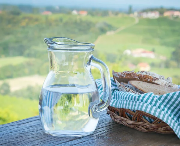 Glass jug with water and bread on a blurred background