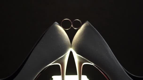 花嫁の結婚式の靴の間に設定された2つの金の結婚指輪クローズアップ — ストック動画