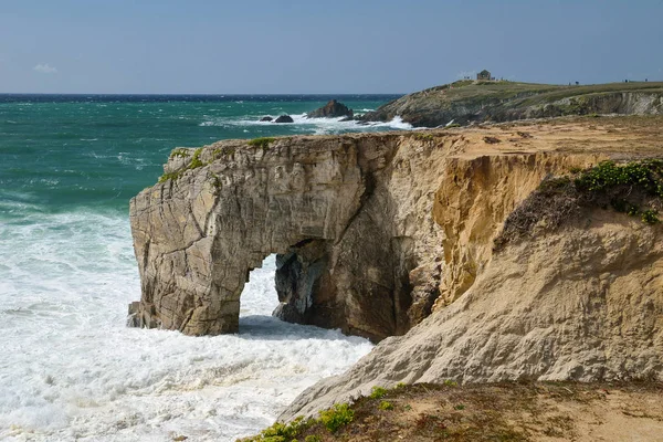 Stormy weather with foamy ocean waves breaking against natural cliffs and stone arch \