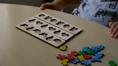 otistik çocuk bir öğretmenin yardımıyla formlarda renkli yapboz toplar