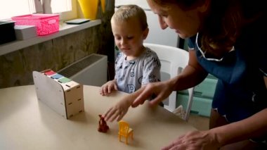 otistik bir çocuk bir asistan görevini gerçekleştirmek için çalışır - bir sandalyeye bir pisi koymak için