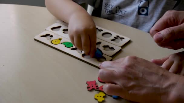 enfant autiste recueille des puzzles colorés dans des formes avec l'aide d'un enseignant 