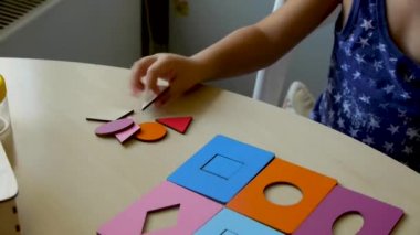 otistik çocuk bir asistan ile sınıfta renkli bulmacalar toplar ve hatalar yapar. Close