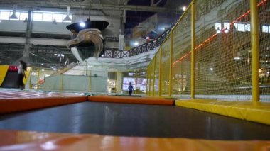 Otistik bir çocuk koşar ve trambolin salonunda bir trambolin atlar. Çocuk uzaktan doğrudan kameraya yaklaşıyor.