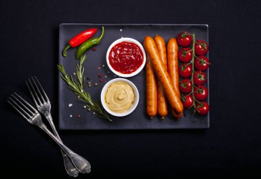 Wiener sosis siyah arka plan üzerine bir tabak içinde baharatlar ile. Kopya alanı ile üstten görünüm.