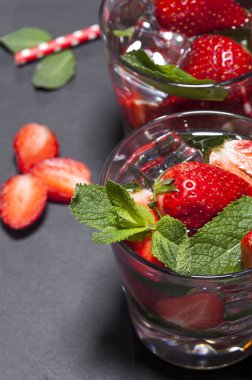 Çilek, nane ve buz cam siyah arka plan üzerine yaz soğuk içecek. Taze berry meyve ile kokteyller closeup.