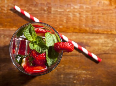 Çilek, nane ve buz cam ahşap zemin üzerine yaz soğuk içecek. Closeup taze berry meyve kokteyli.