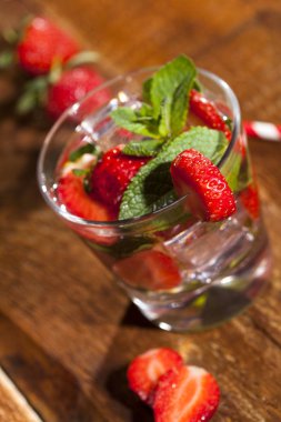 Çilek, nane ve buz cam ahşap zemin üzerine yaz soğuk içecek. Taze berry meyve ile kokteyller closeup.