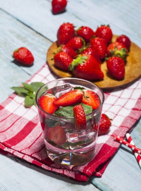 Çilek, nane ve buz cam mavi ahşap zemin üzerine yaz soğuk içecek. Taze berry meyve ile kokteyller closeup.