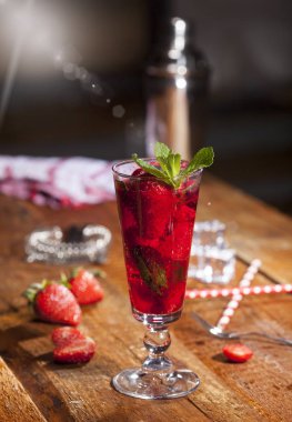 Çilek, nane ve buz cam üstünde ahşap bar sayaç ile yaz soğuk içecek. Closeup taze berry meyve kokteyli.