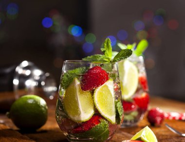 Çilek, nane, limon ve buz cam üstünde ahşap bar sayaç ile yaz soğuk içecek. Closeup taze berry meyve kokteyli.