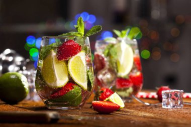 Çilek, nane, limon ve buz cam üstünde ahşap bar sayaç ile yaz soğuk içecek. Closeup taze berry meyve kokteyli.