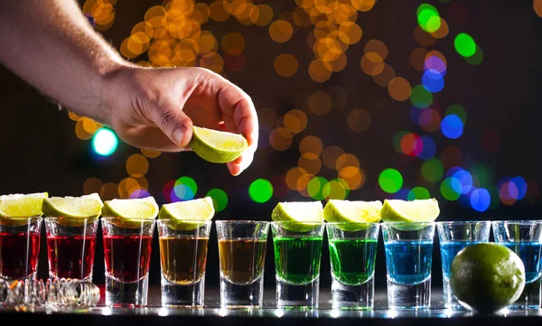 小さなグラスに酒のバー バーではカラフルなカクテル クラブでカラフルなショット 異なる色のアルコール飲料です ナイトライフ シーン バーでショット テーブル — ストック写真
