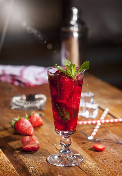 Çilek, nane ve buz cam üstünde ahşap bar sayaç ile yaz soğuk içecek. Closeup taze berry meyve kokteyli.