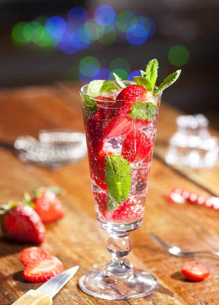 Çilek, nane ve buz cam üstünde ahşap bar sayaç ile yaz soğuk içecek. Closeup taze berry meyve kokteyli.