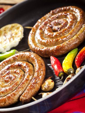 Sebze ve baharat bir tavada ızgara sarmal sosis closeup