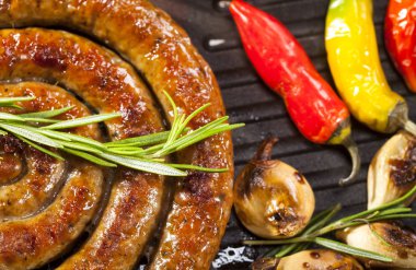 Sebze ve baharat bir tavada ızgara sarmal sosis closeup