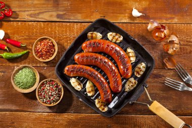 Sebze ve baharat ahşap arka plan üzerinde bir tavada ızgara sosis