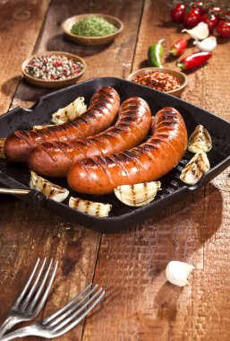 Sebze ve baharat ahşap arka plan üzerinde bir tavada ızgara sosis