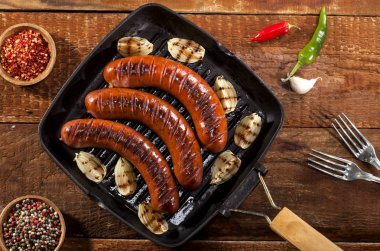 Sebze ve baharat ahşap arka plan üzerinde bir tavada ızgara sosis