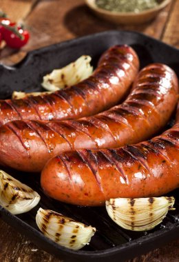 Sebze ve baharat ahşap arka plan üzerinde bir tavada ızgara sosis